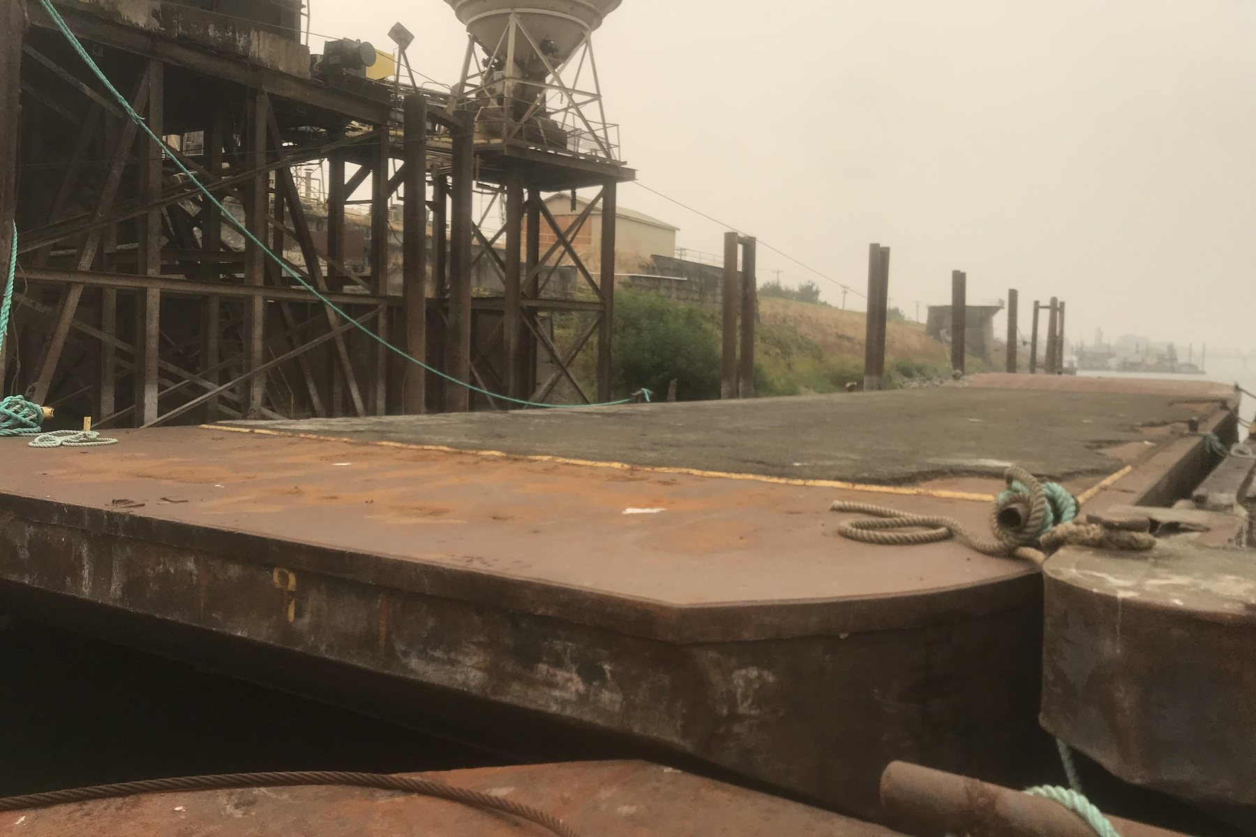 AX9 flat-deck material barge moored at industrial facility